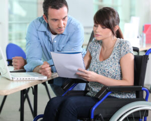 Support worker reviewing paperwork with woman in wheelchair, showing efficient NDIS staff support
