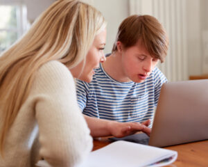 Smiling support worker and participant reviewing NDIS participant dashboard on laptop